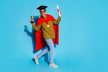 Full size photo of pretty young male receive diploma golden goblet walk wear trendy plaid outfit isolated on blue color background