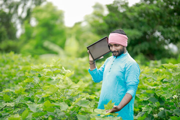 happy young Indian farmer using smart phone