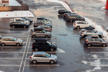 View from above on car parking with many vehicles and free lots at bright early frosty cold winter morning. Parking lot with snowdrifts near airport terminal or shopping business mall at cold weather © Kirill Gorlov