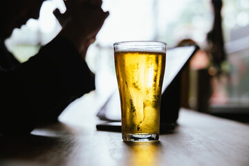 A man pours frothy beer into a glass at a lively pub. Friends gather around the bar, enjoying drinks and celebrating, with a warm, golden glow highlighting the joyful, friendly atmosphere.