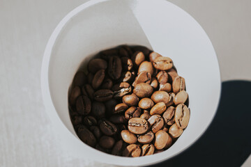 White cup with roasted coffee beans top view. The concept of quality coffee and roasters