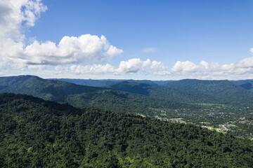 Fototapeta premium Beautiful aerial view of lush green forest and mountains under cloudy sky.
