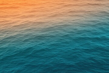 Obraz premium A gradient moving from a warm orange to a cool teal with a subtle grain effect, resembling a sunset over the ocean.