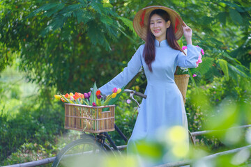 A pretty Vietnamese young Asian woman wearing an Ao Dai a traditional Vietnamese dress a National costume blue color Ao Dai is popular in the green natural rice field. Model portrait fashion.