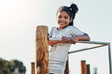 Monkey bar, playing and portrait of child in park for fun, joy or summer break in countryside. Happy, excited and girl kid on wooden jungle gym equipment in outdoor playground with smile for holiday.