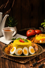 Traditional Indonesian Nasi Kuning dish featuring yellow rice various side dishes