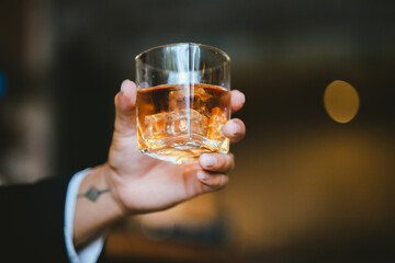 Whiskey drinks at the bar celebrating a special event in a luxury bar. Close-up shows a cheerful atmosphere as glasses clink together, reflecting a lively and joyful gathering.