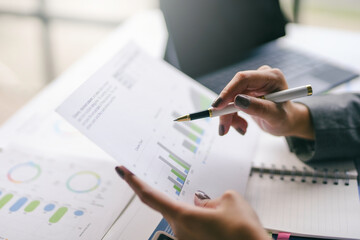 Business team working together, analyzing financial charts and graphs on paperwork with laptop computer in office