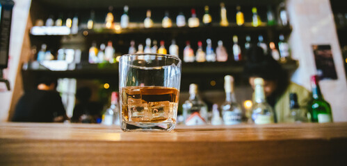 Whiskey drinks at the bar celebrating a special event in a luxury bar. Close-up shows a cheerful atmosphere as glasses clink together, reflecting a lively and joyful gathering.