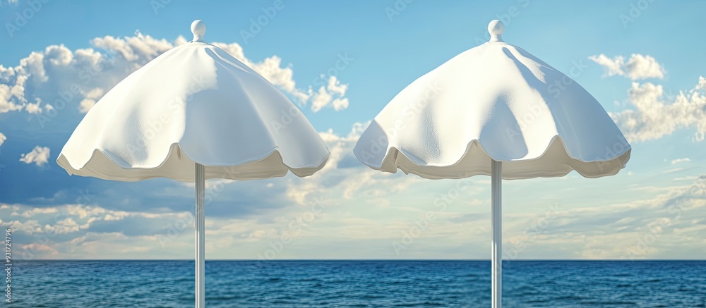 Poster Close up of two closed white canvas beach umbrellas set against a backdrop of the sea and a blue sky with clouds. with copy space image. Place for adding text or design