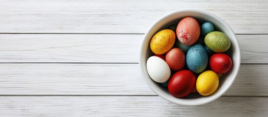 Easter greeting card featuring a bowl of colorful eggs on a white wooden table Includes space for your greetings. with copy space image. Place for adding text or design