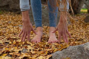 Hands and bare feet of woman stretching in nature in autumn