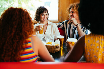 Multiethnic group of friends having meal at 80s vintage diner restaurant - Multiracial young people bonding and having fun, eating in an american fast food burger house