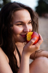 Girl eats juicy peach on the beach. Ripe peach.