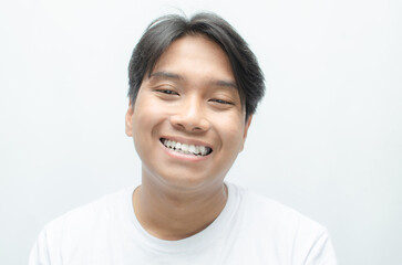 young asian man smiling and showing his crooked teeth isolated over white background. dracula teeth...