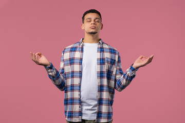 Calm young man relaxing, meditating, refuses stress. Breathes deeply on pink