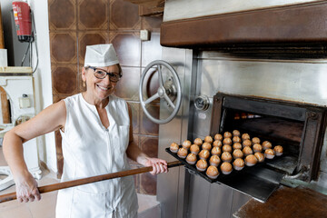 Baker taking freshly baked pastries out of the oven