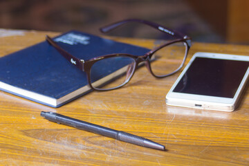 pen smart-phone Glasses and book on wood table for business or education concept