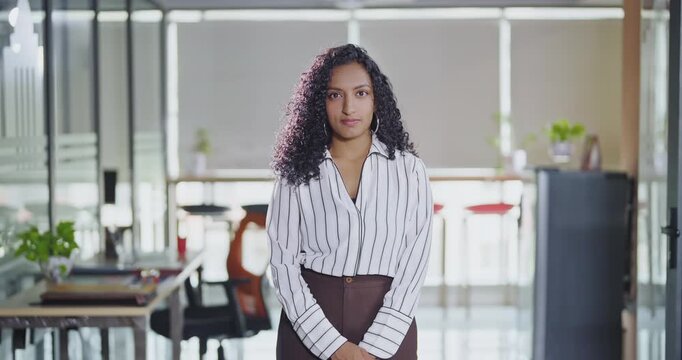 Indian Asian curly hair young adult gen z cute teen age expert girl cross arms standing proud look cam indoor office day happy woman lady staff agent fold hand do pose head shot video job work place	
