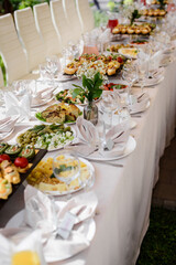 Сatering table with food, flowers and glass stemware at restaurant before party	