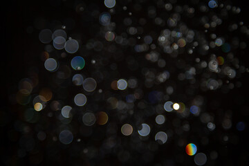 Abstract bokeh lights with colorful circles on dark background, creating a dreamy and festive...