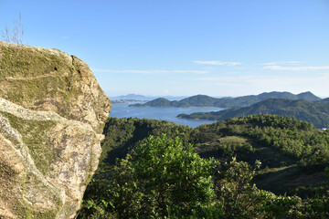A large rocky outcrop overlooks the ocean and islands of Hong Kong
