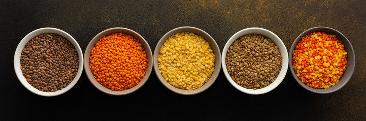 Multicolored lentils in bowls banner, yellow and brown, green and orange lentils, healthy legumes, top view, copy space