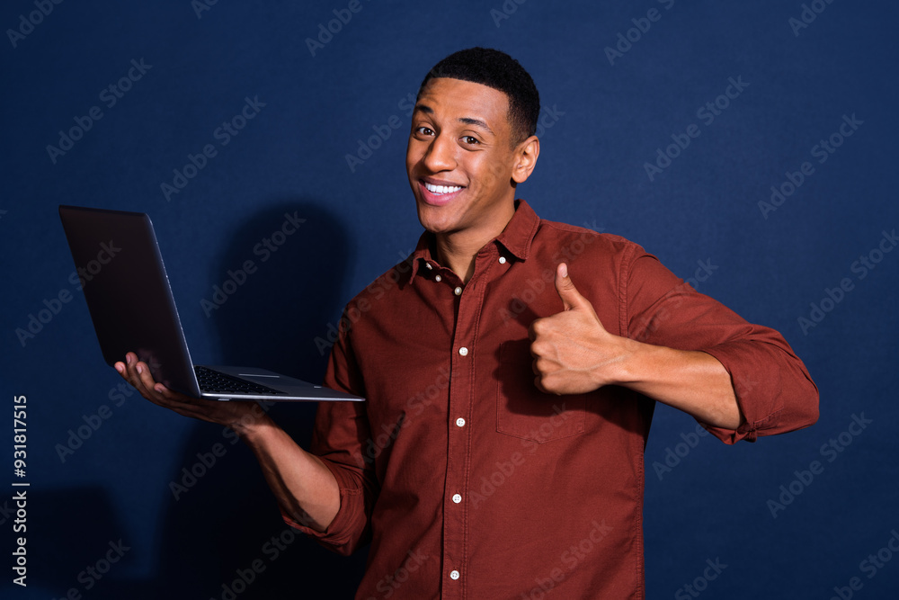 Poster Photo of cool confident guy dressed brown shirt modern device showing thumb up isolated blue color background