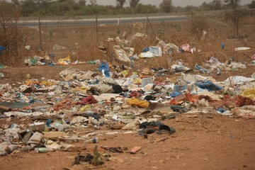 Vue rapprochée d'une décharge sauvage au Sénégal composée de déchets en plastique et d'emballages en carton et située près d'une route. Symbole de la pollution et de la dégradation de l'environnement.