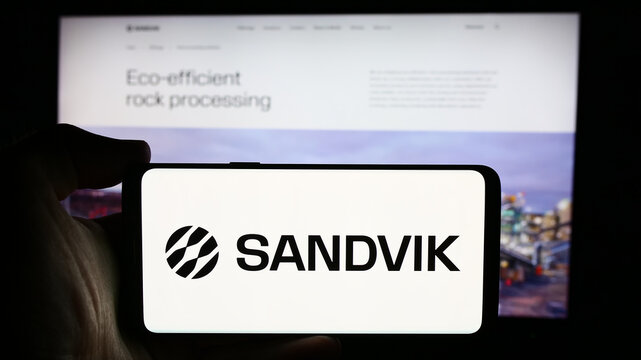 Stuttgart, Germany - 08-15-2024: Person holding cellphone with logo of Swedish engineering company Sandvik AB in front of business webpage. Focus on phone display.