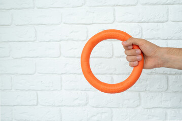 Man hand holding a blue puppy ring toy for teeth with knot tugger. Best dog toys for training and education, and scratching on white background, copy space