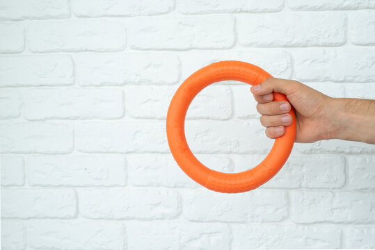 Man hand holding a blue puppy ring toy for teeth with knot tugger. Best dog toys for training and education, and scratching on white background, copy space