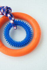Orange puppy pull ring and blue knot tugger. Best dog toys for training and education, and scratching teeth on white background.