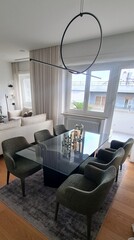 Modern Living and Dining Area with Circular Pendant Light, Glass Table, and Comfortable Upholstered Armchairs
