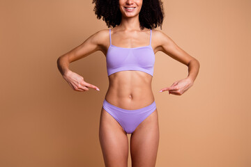 Unretouched photo of pretty model girl point fingers thin waist isolated on beige color background