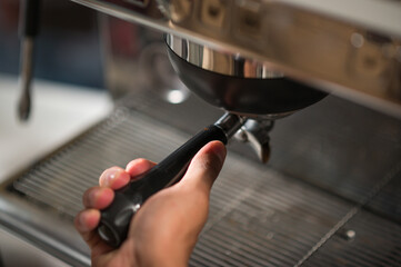 Latin hands take the filter holder from the machine to make an espresso.