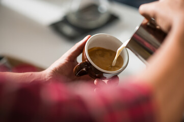 Barista adds hot milk to a cup of coffee.