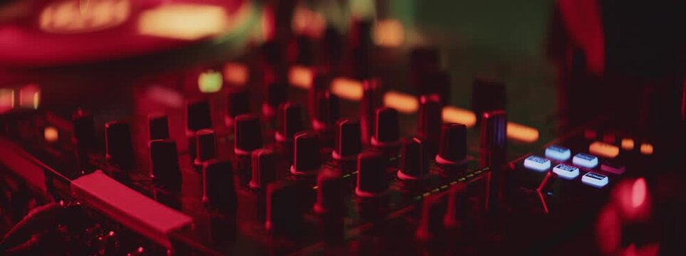 DJ manipulating audio equipment, mixing electronic music at techno party. Talented musician plays his set on turntable. Close-up