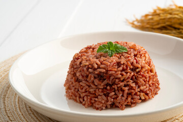 Cooked Thai Organic Red Jasmine Rice in white plate.semi-milled rice.including fiber, B vitamins and magnesium, offering a richer nutritional profile than traditional white rice.