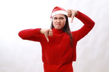 Beautiful hispanic woman wearing christmas hat and red turtleneck showing thumbs down, difficult choose concept