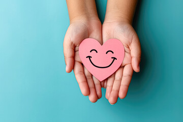 Obraz premium A child is holding a pink heart with a smiley face on it