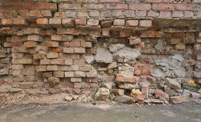 old half destroyed red brick wall with a pile of rubble