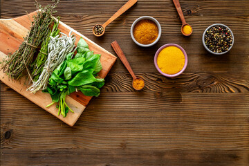 Colorful spices in wooden bowls and green herbs for cooking, top view