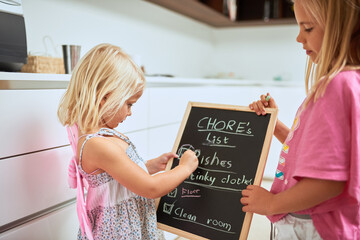 Children, chalkboard and checklist of chores in home, writing or reading for help, team or...
