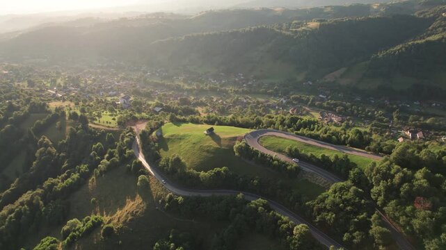Aerial scene above the Rucar - Bran pass, in Transylvania, during summer. Cars driving on a beautiful mountain road, at sunrise