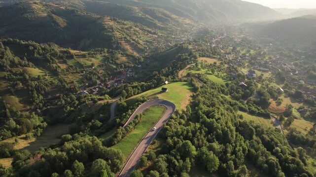 Aerial scene above the Rucar - Bran pass, in Transylvania, during summer. Cars driving on a beautiful mountain road, at sunrise