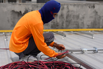 Close-up of a worker installing solar panels. A worker installs solar panels at a solar farm field..