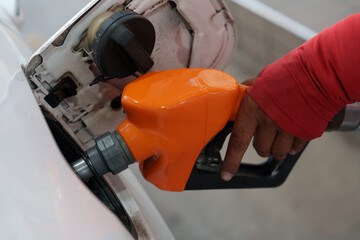 Close-up of gas station attendant's hand with orange fuel nozzle