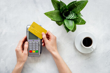 Hands holding Pos bank terminal for payment by credit card, bill for cup of coffee in cafe