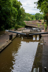 Chester Cheshire UK. Serene canal lock surrounded by lush greenery and historic brick pathways on a cloudy day.